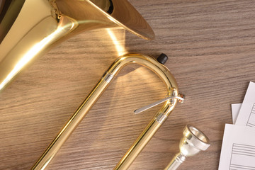 Disassembled golden trombone and scores on wooden table detail glitters