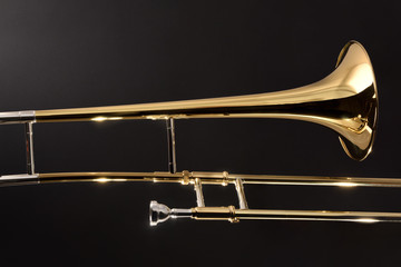 Golden trombone close-up with dark background - obrazy, fototapety, plakaty