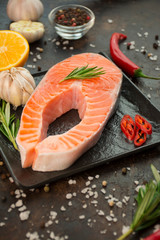 Salmon fillet with aromatic herbs, spices and vegetables on a dark background. Cooking concept. Culinary background. Food background. Healthy food balance. Table background menu. Copy space.