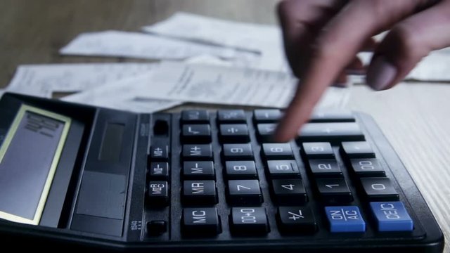 A woman with checks counts on the calculator a family budget. Family budget.  Savings, finances and economy concept