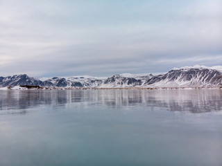 Fototapeta na wymiar Snow covered mountains in Iceland with reflection in a frozen lake 