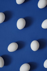 Pattern with white eggs on blue background. Top View. Copy Space. Pop art design, creative food concept. Banner. Eggs in minimal flat lay style