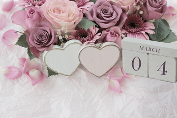 Calendar. March 4th. Wood cube calendar with date of month and day, pink flowers bouquet and two hearts. Greeting card for various holidays. Invitation. Copy space.