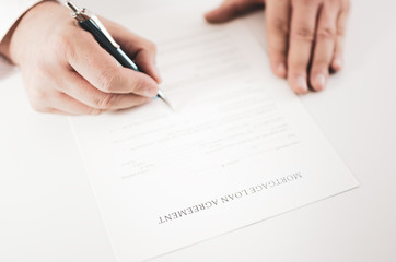 Closeup of a businessman  signing a mortgage loan  agreement with a pen.