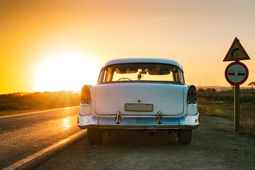 baby blue and white classic car on the road at sunset in cuba - obrazy, fototapety, plakaty