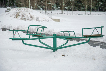 green steel carousel in the snow without children