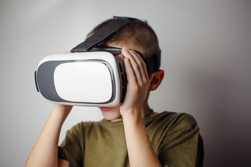 Boy playing mobile game app on device virtual reality glasses on white background. Boy action and using in virtual headset, VR box for use with smart phone. Contemporary technology concept