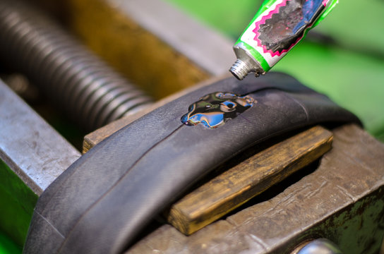 Repairing bicycle tube In workshop. Close up image of glue to repair inner tube of bicycle wheel. The mechanic does his job thoroughly.