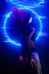Cyberpunk style portrait of beautiful young girl poses underwater against glowing circle. Picture...