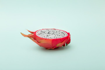 One half of dragon fruit or pitaya on green background.