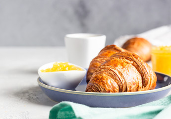 French breakfast with fresh pastries. Croissants with coffee and jam. Light grey stone background. 
