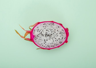 One half of dragon fruit or pitaya on green background.