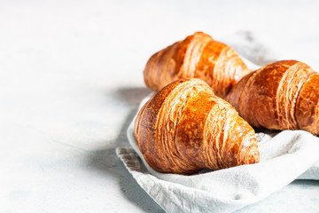 Fresh croissants on a grey linen napkin. Light grey concrete background. 