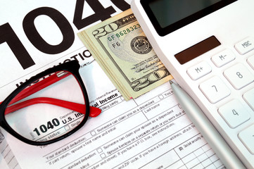 Income tax form with with instruction, money, calculator and glasses