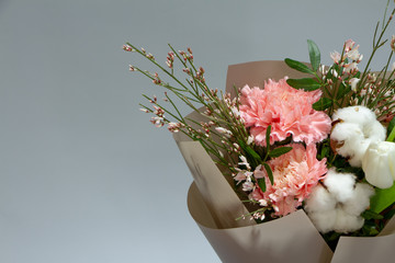 Close-up fresh bouquet of carnation, tulip, cotton, genista, pistachio on a gray background, selective focus