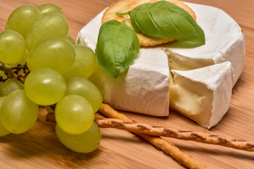 Camenbert mit Weintrauben, Weintrauben, Salzstangen, Basilikum, angerichtet. appetitlich, angeschnitten, Rahm reif, wei&szlig;, lecker, K&auml;seecke