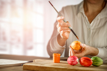 Obraz premium Hands painting Easter eggs on wooden table during spring time