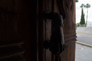 Iron hand door knocker on old wooden door.