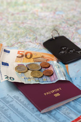 Banknoty i monety Euro leżą na mapie samochodowej. Paszport i kluczyki samochodowe również leżą na papierowej mapie. - obrazy, fototapety, plakaty