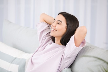 Young woman sitting on sofa at home