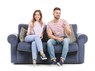 Obraz premium Young couple with mobile phones sitting on sofa against white background