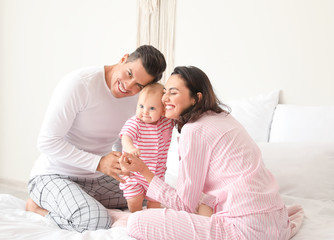Cute baby with parents in bedroom