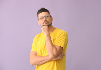 Thoughtful man wearing glasses on color background