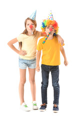 Little children in funny disguise and with party whistles on white background. April fools' day celebration