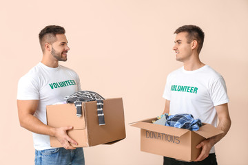 Volunteers with donations for poor people on color background