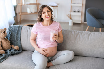 Beautiful pregnant woman drinking yogurt at home