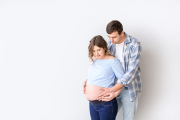 Beautiful pregnant couple on grey background