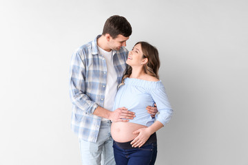 Fototapeta premium Beautiful pregnant couple on grey background
