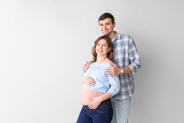 Fototapeta premium Beautiful pregnant couple on grey background