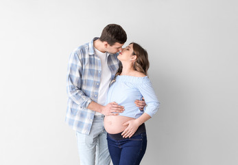 Beautiful pregnant couple on grey background