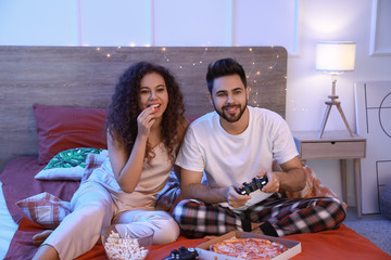 Happy young couple playing video games in bedroom