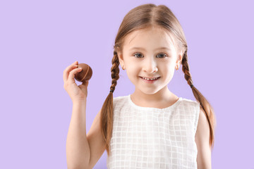 Cute little girl with sweet chocolate egg on color background