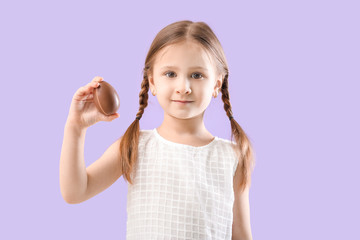 Cute little girl with sweet chocolate egg on color background