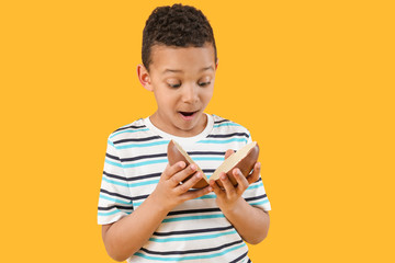 Cute African-American boy with sweet chocolate egg on color background