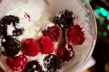 Cropped shot of an ice cream, red  raspberries and blackberry. Abstract food background.  Yogurt and berries, close up, top view.