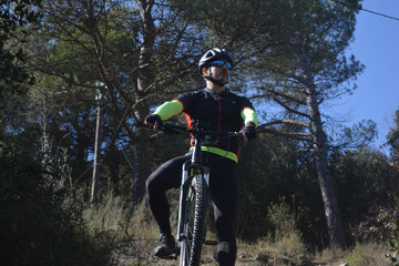 Male cyclist with a mountain bike observing the landscape in the forest