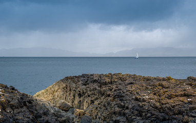 Rocks, sea and sailing boat scottish landscape. Tobermory, Island of Mull, Scotland.