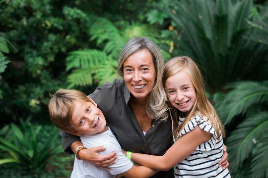 Mother And Children Embracing By Bush