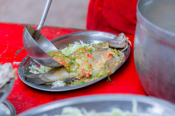 Steamed sea bass fish with lemon, Thai famous local food served on fish shape plate. Thai recommend menu for tourist. Steamed fish with herb and lemon, topped with spicy sour sauce. PLA NERNG MANAW.