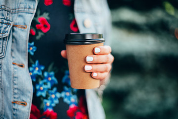 Female hand with paper cup of coffee take away.