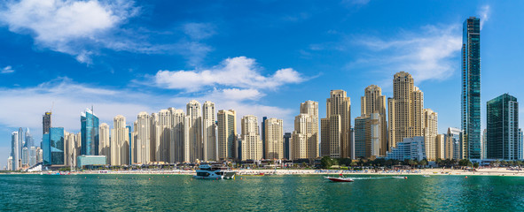 Obraz premium Panorama of skyscrapers on coast of Dubai Marina, view from water, UAE.