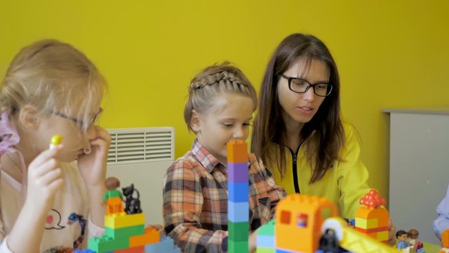 Children in the classroom make figures with teacher. Modern technology concept