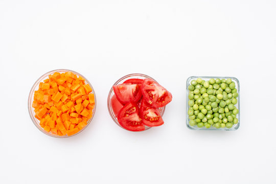 Zanahoria, jitomate y chicharo para hacer arroz rojo en recipientes de cristal con fondo blanco