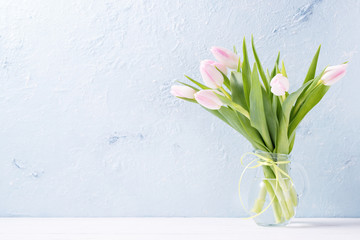 Pink fresh tulips in a vase on a wooden table, copy space
