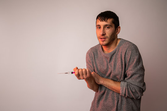 The Guy Is An Evil Addict With A Syringe In His Hand, Sloppy Male Feeling High Isolated Over Grey Background