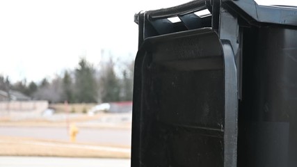 Wind blowing garbage can lid back and forth